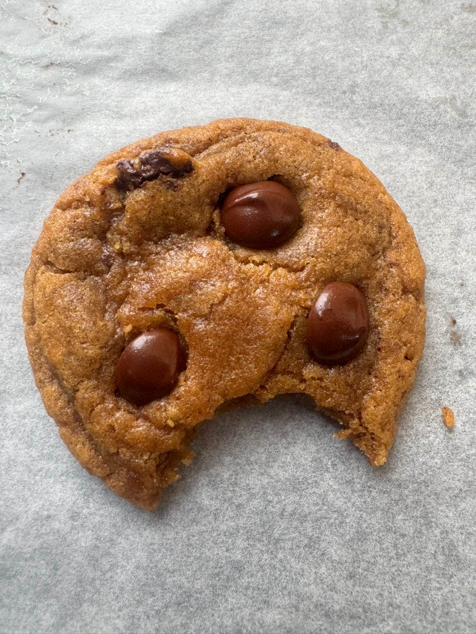 Single brown butter chocolate chip cookie with a bite taken